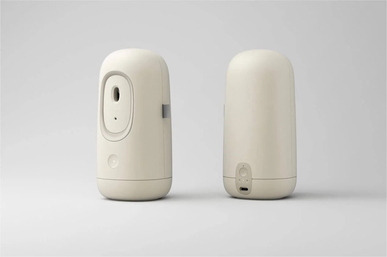 Two beige automatic air freshener units side by side, one showing the front and the other the back, on a neutral background.