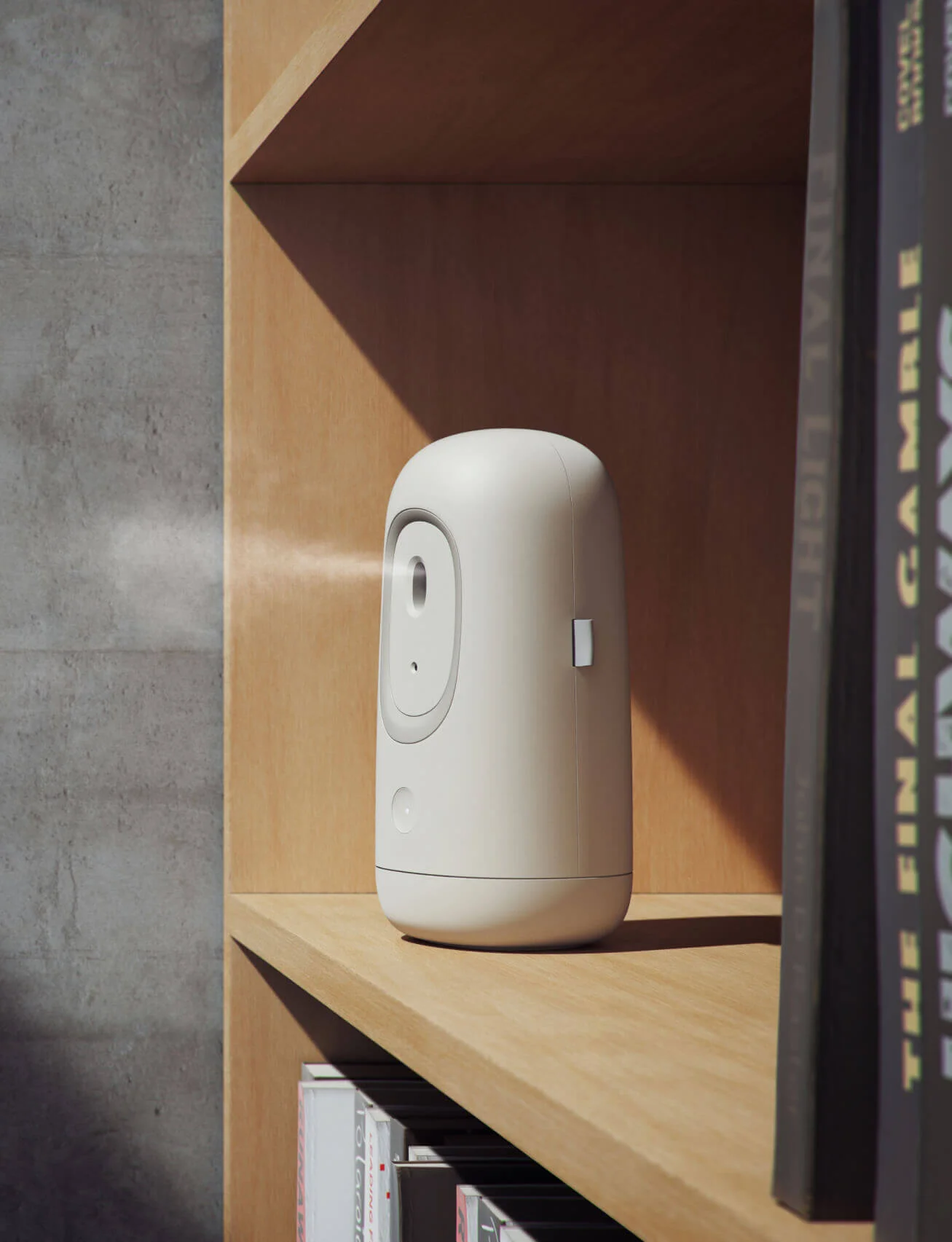 Automatic air freshener, designed by Studio Copilot, standing on a wooden shelf beside books, emitting a gentle mist.